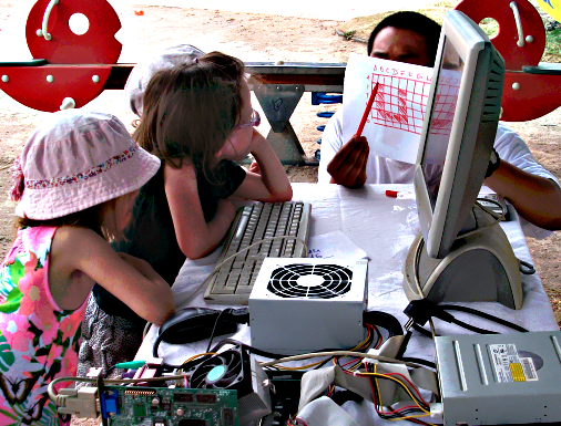 Pictogramme pour Animateur interviewant un enfant devant une table 
                disposée en plein air